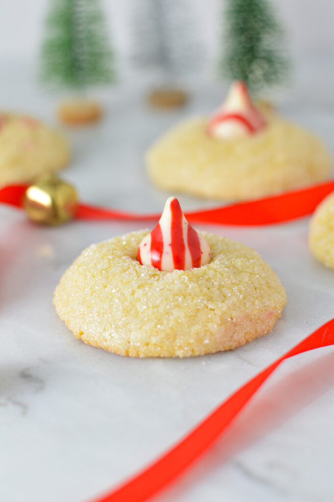 Peppermint Kiss Cookies with a red and white stripped Hershey's peppermint kiss on top of a fluffy cookie rolled in sparkling sugar.