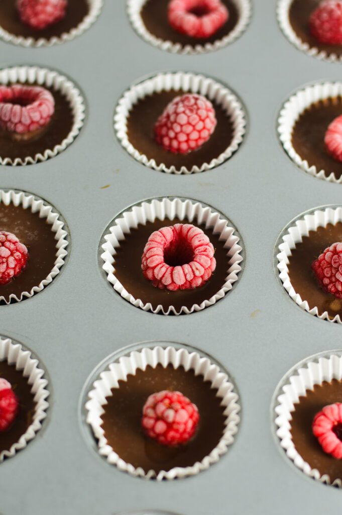 A mini muffin pan filled with Raspberry Nutella Cups in mini paper liners.