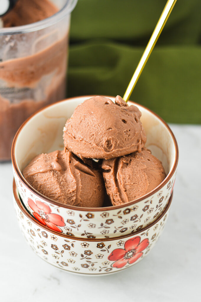 A bowl of creamy Ninja Creami Lite Chocolate Pudding Ice Cream, with a gold spoon sticking out of the bowl.