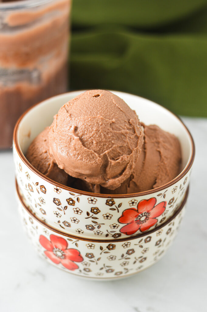 A bowl of dark brown creamy Ninja Creami Lite Chocolate Pudding Ice Cream, with the scoops clearly showing the velvety texture of the frozen treat.