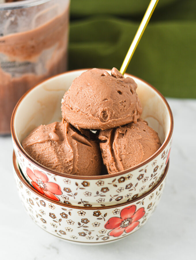 Scoops of Ninja Creami Lite Chocolate Pudding Ice Cream inside a small bowl, with a small golden spoon sticking out of the homemade ice cream.