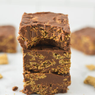 A stack of Peanut Butter and Chocolate Chex Bars with a bite taken out of the top bar, showing the fudgy texture.