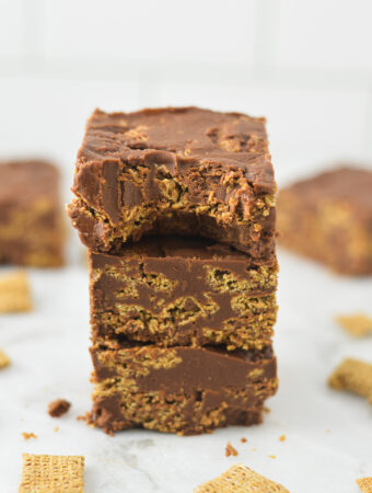 A stack of Peanut Butter and Chocolate Chex Bars with a bite taken out of the top bar, showing the fudgy texture.