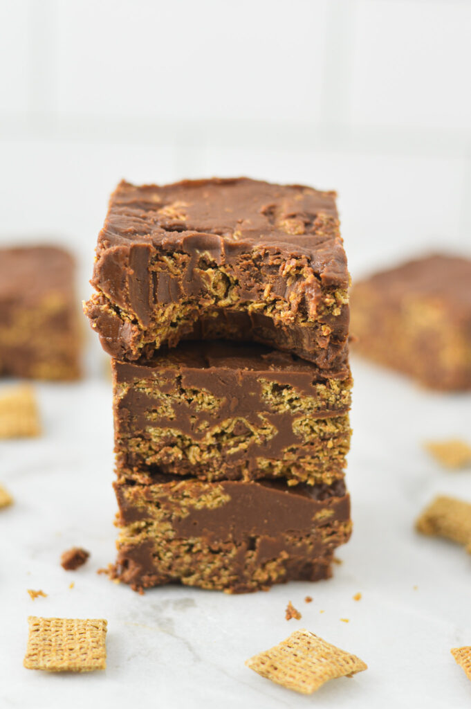 A stack of Peanut Butter and Chocolate Chex Bars with a bite taken out of the top bar, showing the fudgy texture.