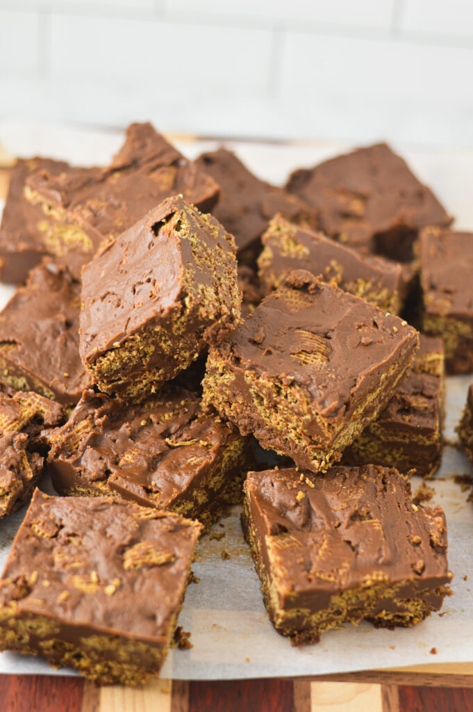 A pile of Peanut Butter and Chocolate Chex Bars on a parchment paper lined cutting board.