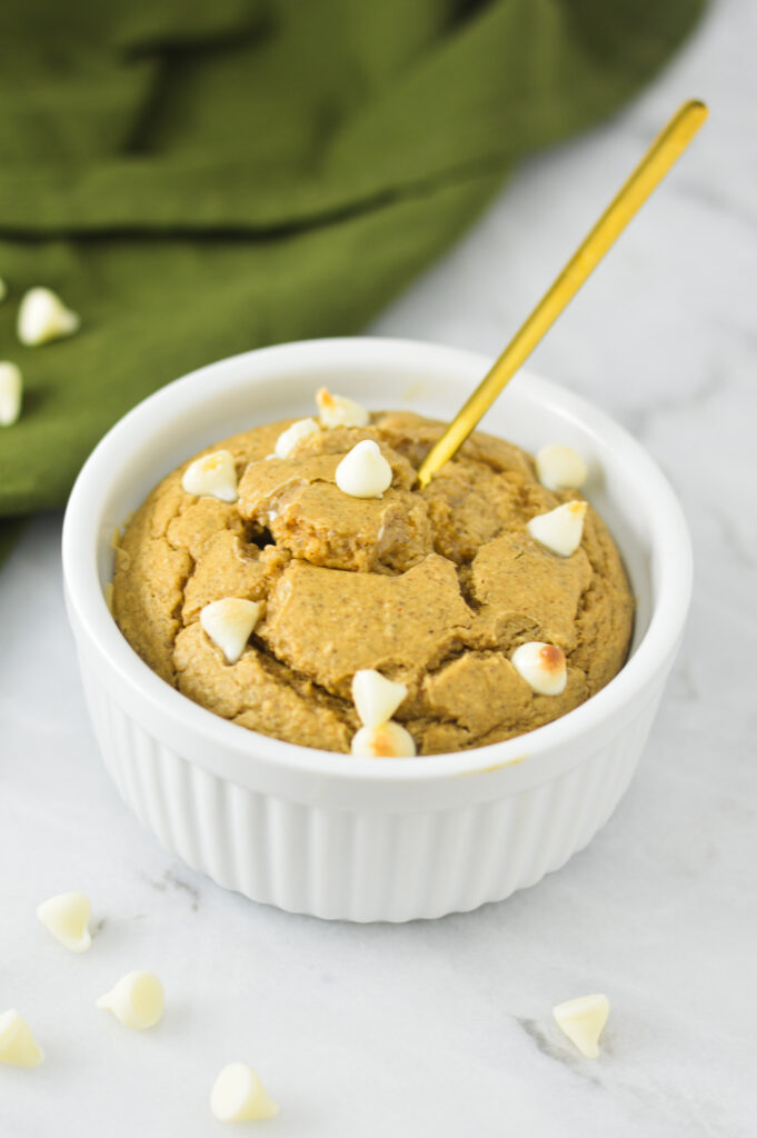 A small spoon inserted into the middle of some White Chocolate Protein Blended Baked Oats in a white ramekin.