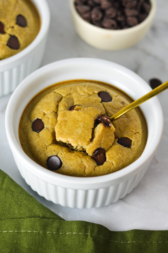 A small spoon inserted into a ramekin full of fluffy Chocolate Chip Protein Blended Baked Oats.