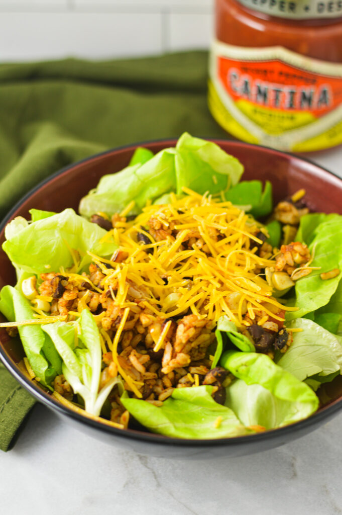 Rice and Black Bean Salad in a bowl with a jar of salsa in the background.