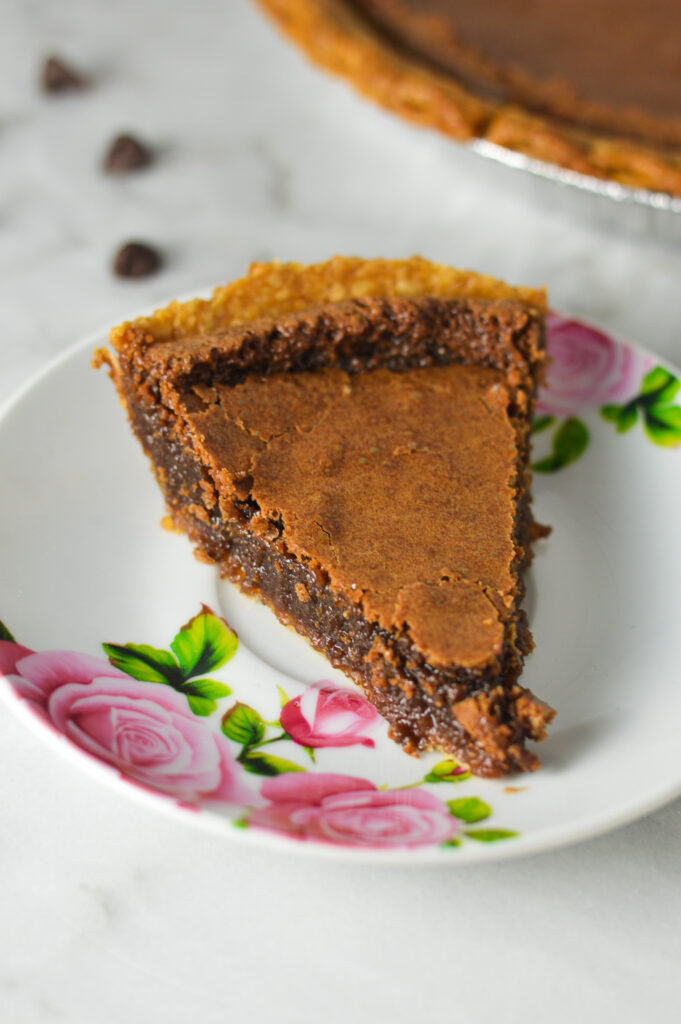 A small floral plate with a slice of Chocolate Chess Pie, showing the rich and fudgy filling.