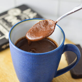 A spoon scooping some Rich Hot Chocolate from a blue mug.